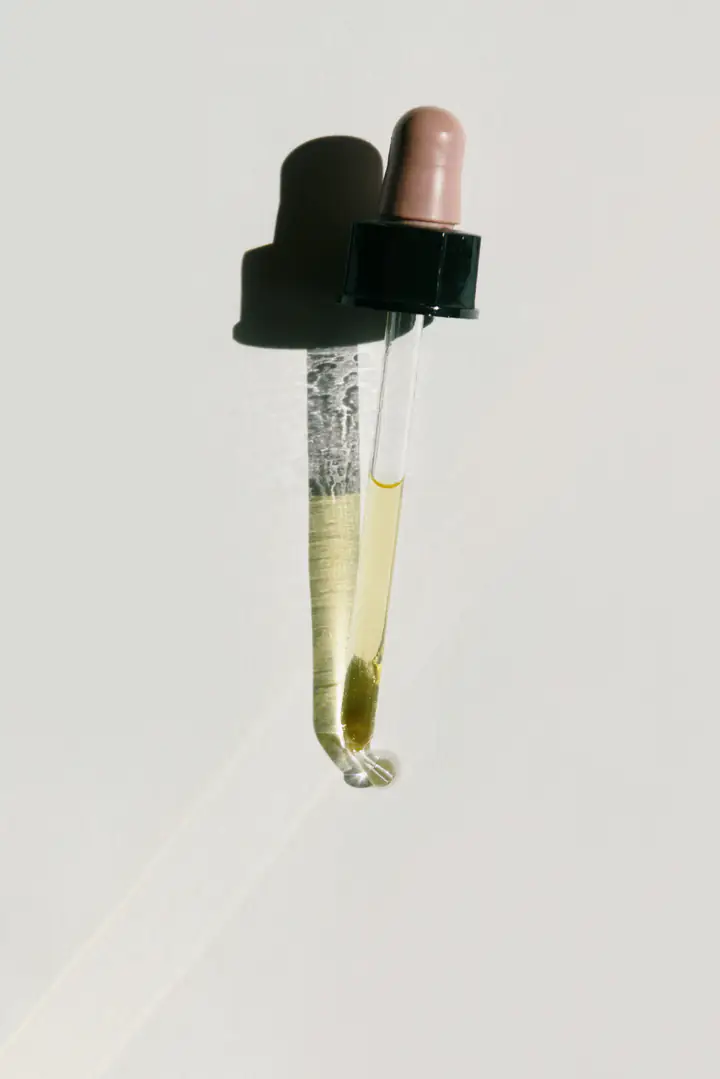 The glass dropper lifted from the bottle, holding pale gold serum